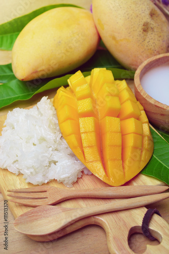 Fototapeta Naklejka Na Ścianę i Meble -  mango with sticky rice on wooden tray. thai dessert made from mango fruit. glutinous rice eat with mangoes and coconut milk. 