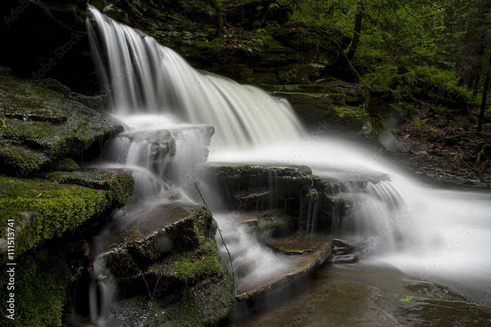 Fototapeta premium A long exposure of a scenic waterfall landscape in a bright green spring forest.