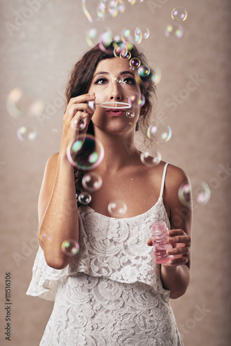 Portrait of young attractive woman blowing soap bubbles