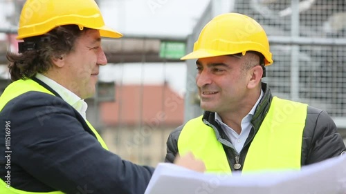 Construction workers laughing reading office blueprints