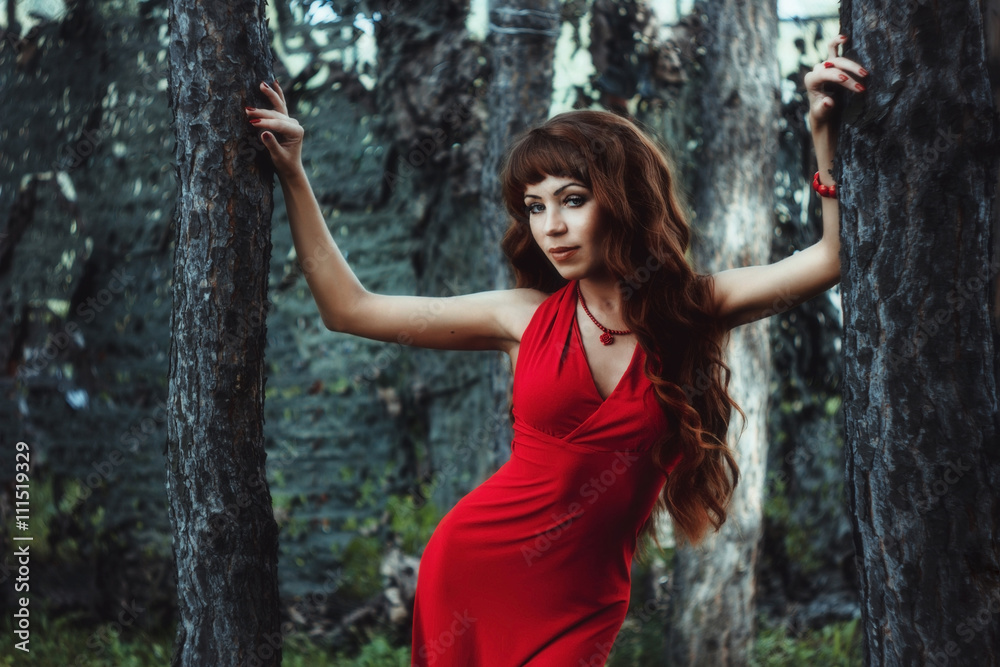 The girl with long wavy hair in a red dress in the forest The girl with long wavy hair in a red dress in the forest