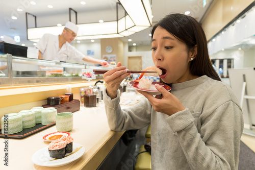 Woman eating sushi in japanese restaurant