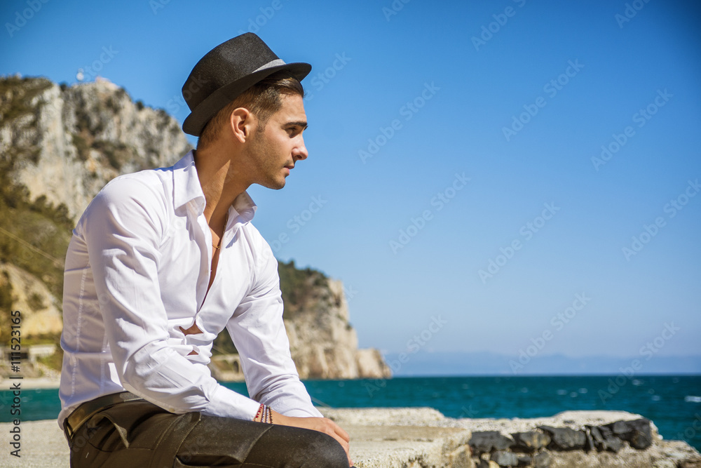 Handsome man in white shirt and hat on beach