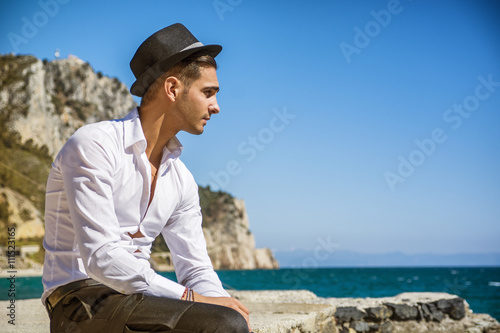 Handsome man in white shirt and hat on beach
