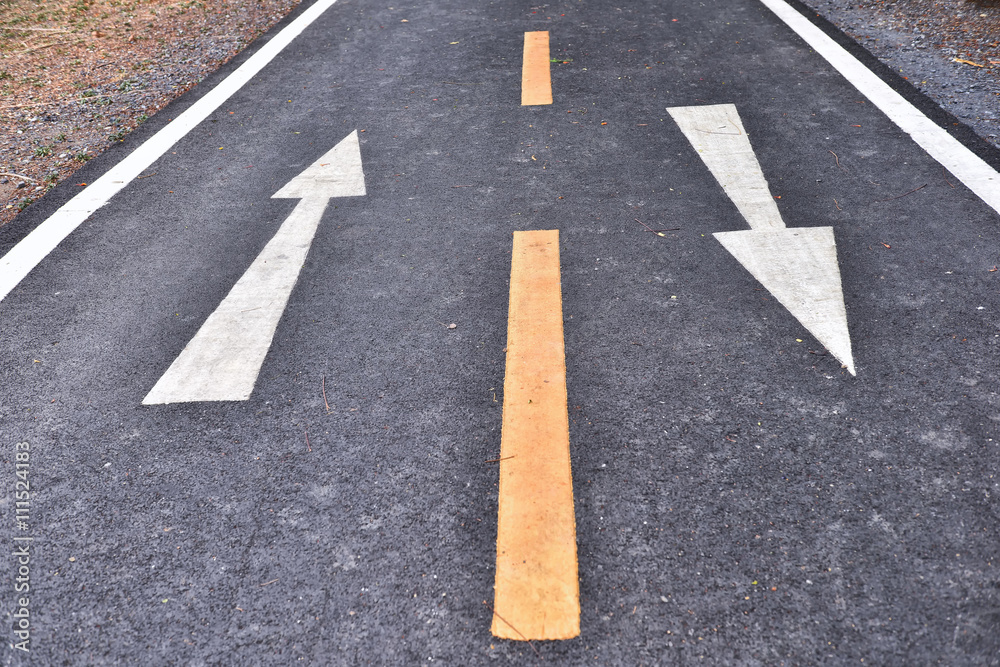 White arrow sign marking on road surface in the park for giving directions