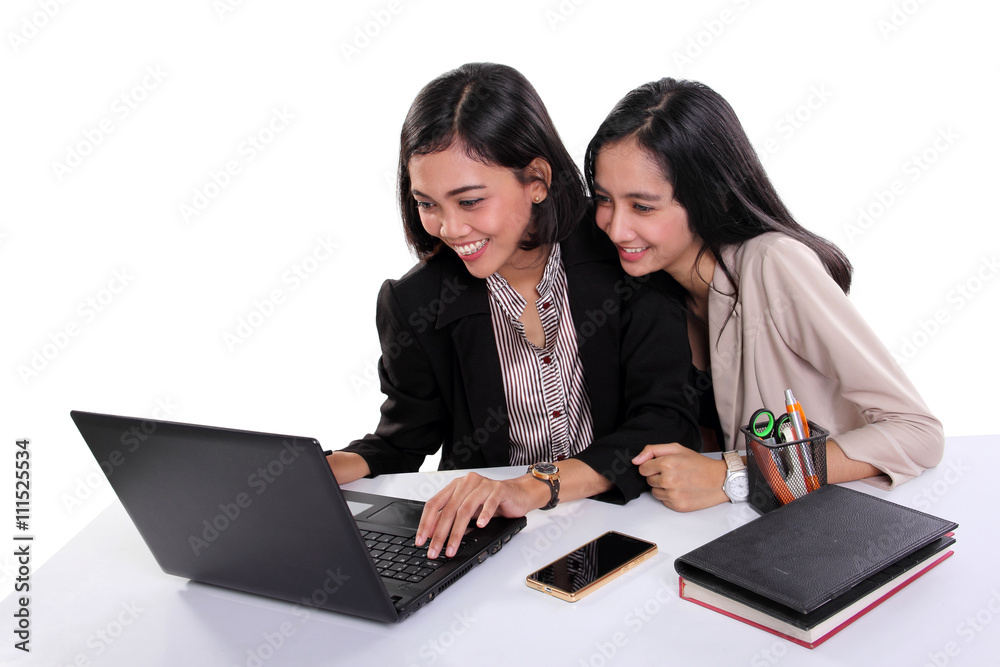 Female office workers using laptop together Female office workers using laptop together