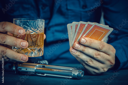 Photography gangster with gun holding whiskey glass and playing poker