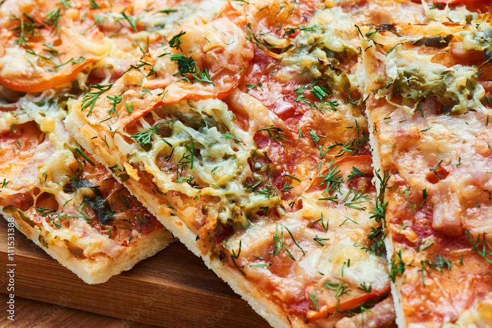 Traditional pizza with ham, cheese and tomatoes sprinkled with greens closeup Traditional pizza with ham, cheese and tomatoes sprinkled with greens closeup