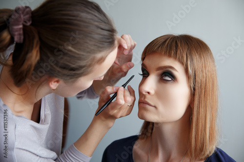 makeup artist glues false eyelashes