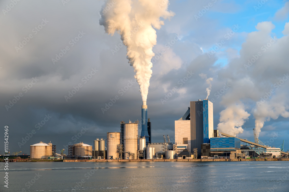 Smoking chimney at sunset on industrial buildings complex. Smoking chimney at sunset on industrial buildings complex.