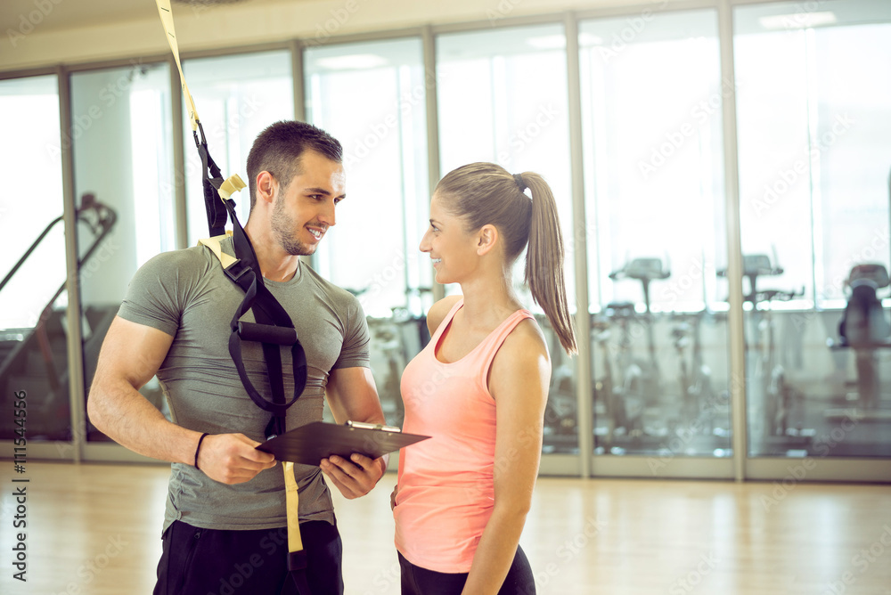 Personal trainer with suspension showing results to client. Personal trainer with suspension showing results to client.