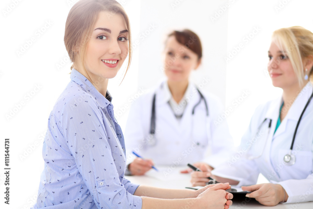 Happy smiling female patient with two cheerful doctors in the background. Medical and health care concept Happy smiling female patient with two cheerful doctors in the background. Medical and health care concept