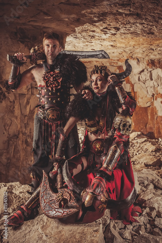Couple of vikings in armor with swords. Catacombs on the backgro