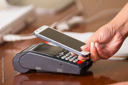 Easy and fast way to pay the shopping accounts, mobile phone near a credit card machine, hand holding mobile phone