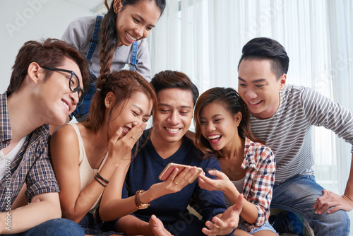 Company of friends watching funny video on smartphone