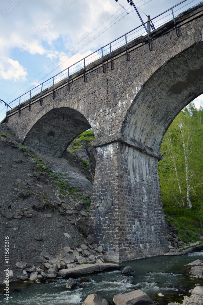 Fototapeta premium Каменный железнодорожный мост через реку
