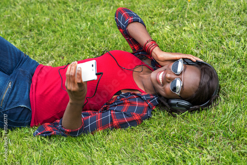 Beautiful smiling african woman with headphones listens to music