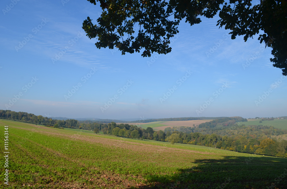 Woman and girl walking on trail through rural landscape with meadows and fields on rolling hills in Wallonia on sunny autumn day, Durnal, Yvoir