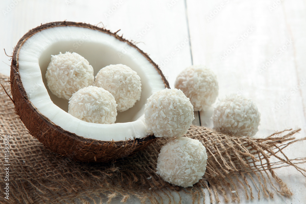 coconut cut into pieces on burlap with candy in coconut chips on a white wooden background coconut cut into pieces on burlap with candy in coconut chips on a white wooden background