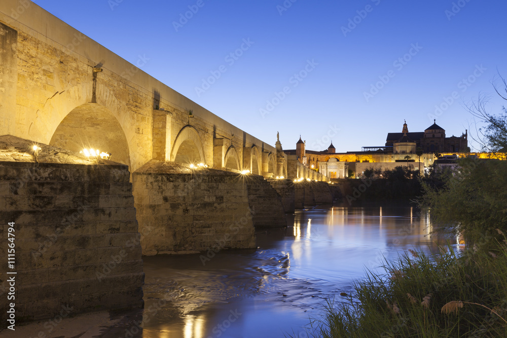 Roman bridge over Guadalquivir river, Cordoba, Spain, at dusk