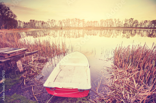 Vintage toned boat by a lake at sunrise