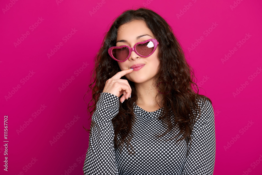 young woman beautiful portrait, posing on pink background, long curly hair, sunglasses in heart shape, glamour concept