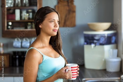Thoughtful woman holding coffee cup in kitchen