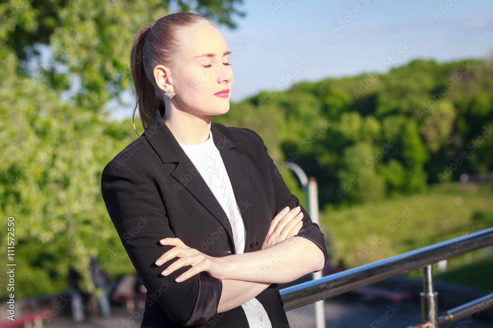 young beautiful businesswoman in a black jacket on the street