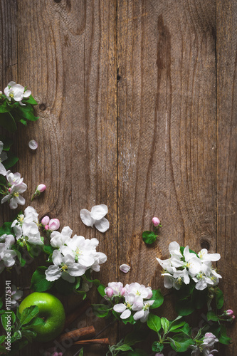 Wooden background with apple blossom flowers. Apple blossoms and green apple on rustic wooden background. Copy space for text. Post card, gift card or wedding card template. Design background