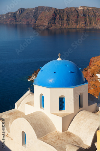 Blue dome church in Oia, Santorini, Greece. Sea and volcano on background
