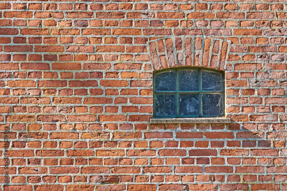 Small iron barn window recessed in a red brick wall. Spider web in the glazing Small iron barn window recessed in a red brick wall. Spider web in the glazing