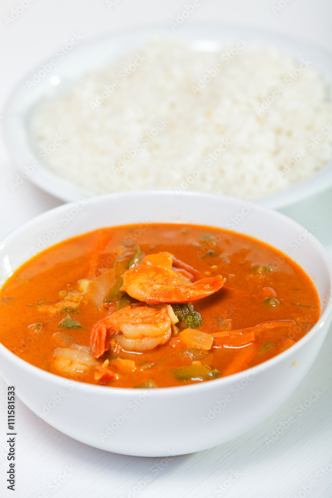 Thai red curry with shrimps, carrots, peppers and onion. Rice on background. Vertical shot Thai red curry with shrimps, carrots, peppers and onion. Rice on background. Vertical shot