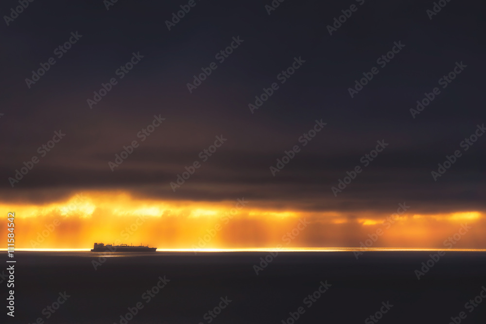 sunrays on the ocean with cargo ship