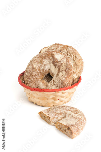 Ciambelle  basse di pane casereccio di farina integrale  nel cestino di vimini isolate su sfondo bianco