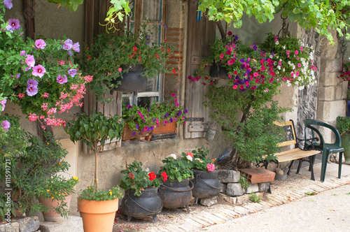A french cottage with lots of hanging baskets, plants and flower pots