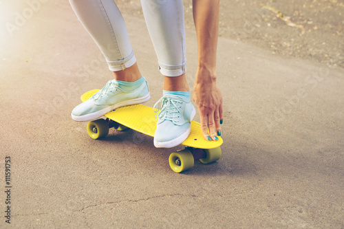 Girl rides on the road on a plastic skateboard in the sunlight © progressman