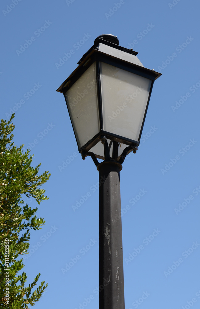 Old fashioned lamp post against a blue sky