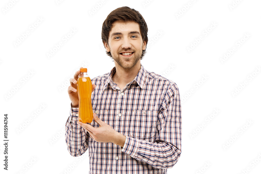 Young handsome cheerful man showing plastic bottle with orange b Young handsome cheerful man showing plastic bottle with orange b
