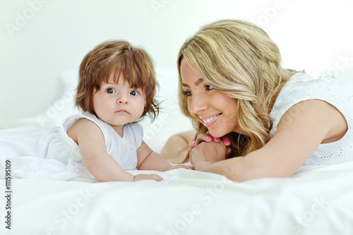 Happy mother with her funny baby on the bedroom