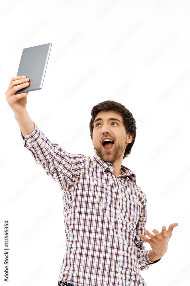 Portrait of handsome smiling young man, having fun making selfie