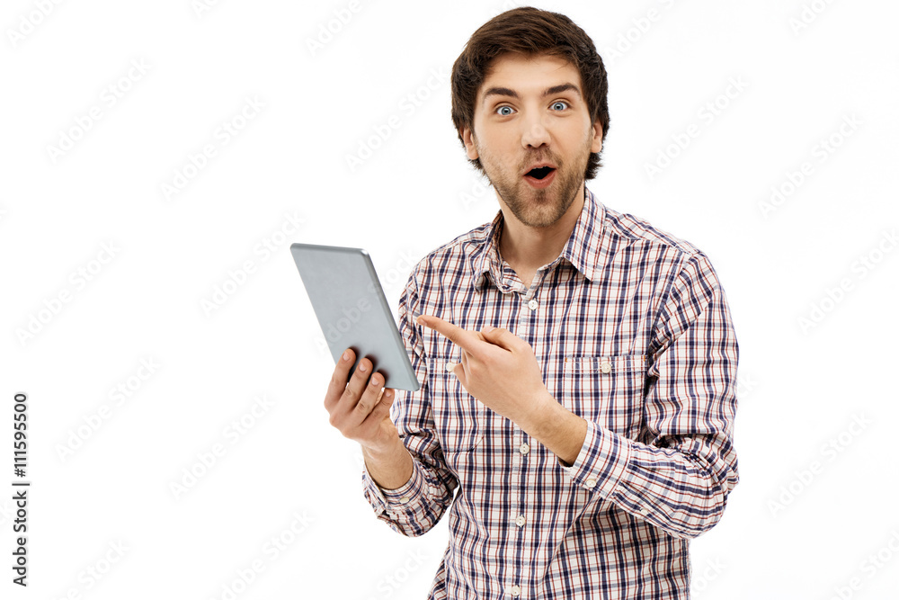 Portrait of handsome surprised young man, pointing on tablet whi Portrait of handsome surprised young man, pointing on tablet whi