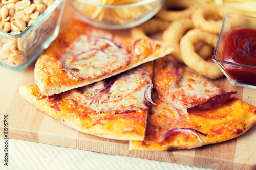 close up of pizza and other snacks on wooden table