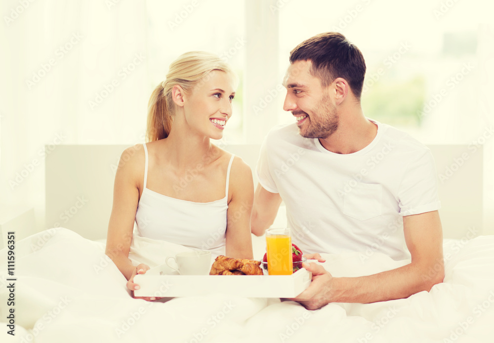 happy couple having breakfast in bed at home