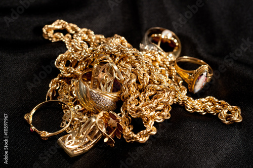 scrap gold jewellery including chains, bracelets and rings on a black background