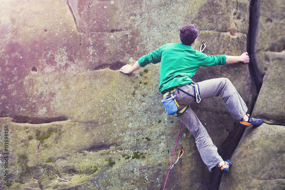 Naklejka premium A rock climber climbs up the mountain.