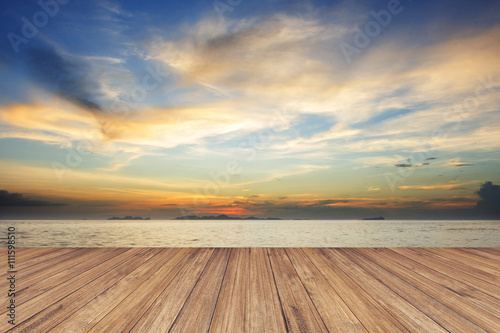 Fotografia Perspective of wood terrace against beautiful seascape at sunset