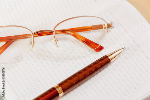 Daily planner with glasses and pen on the table. Selective focus