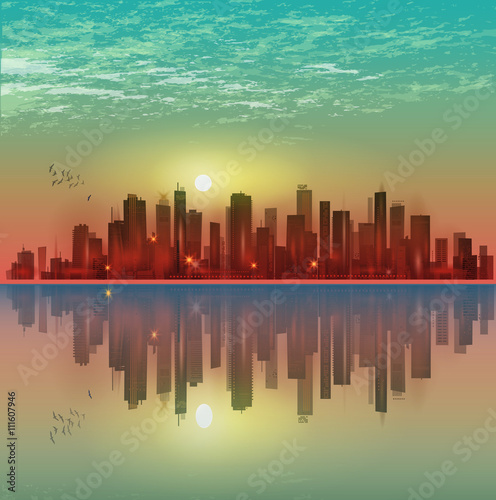 Modern night city skyline in moonlight or sunset, with reflection in water and cloudy sky

