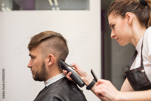 young man cuts hair in the barber shop