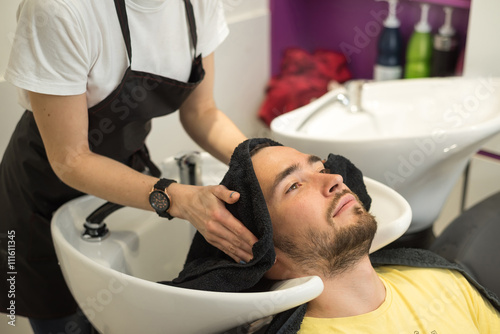 young man washes his head in a hairdressing salon